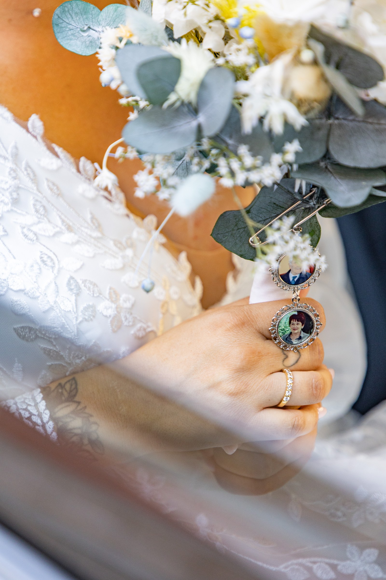 Photo mariage — la main de la mariée et les médaillons souvenirs